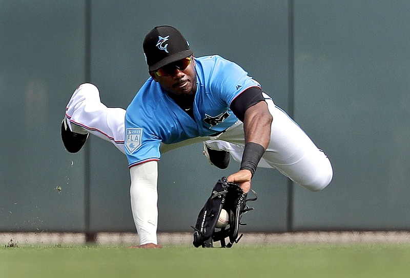 FILE - In this Friday, March 1, 2019 file photo, Miami Marlins center fielder Lewis Brinson dives to catch a fly ball by Washington Nationals' Adam Eaton for an out during the third inning of an exhibition spring training baseball game in Jupiter, Fla. A five-person panel of Major League Baseball players, coaches and executives discussed ways to get more Black people involved at all levels of the sport. Lewis Brinson was on the panel.(AP Photo/Jeff Roberson, File)