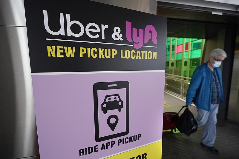 A passer-by pulls luggage while walking past a sign offering directions to an Uber and Lyft ride pickup location at Logan International Airport, in Boston, Tuesday, Feb. 9, 2021. Businesses like Uber, Airbnb and Square were born in recessions. Now, the effects of COVID-19 are forcing existing businesses to reinvent themselves, and some of today's most significant business obstacles will spark new startups offering innovative solutions. (AP Photo/Steven Senne)