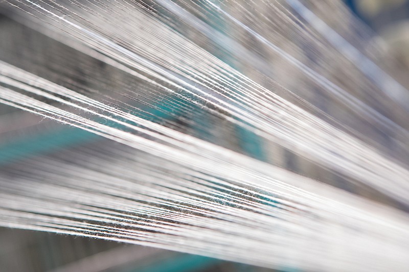 Close up macro detail of synthetic yarn thread lines running in the weaving loom machine. / Photo credit: Getty Images/iStock/yagmradam