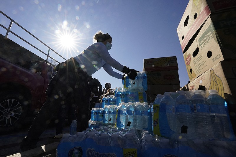 Volunteers load water for people at a San Antonio Food Bank drive-through food distribution site held at Rackspace Technology, Friday, Feb. 19, 2021, in San Antonio. (AP Photo/Eric Gay)