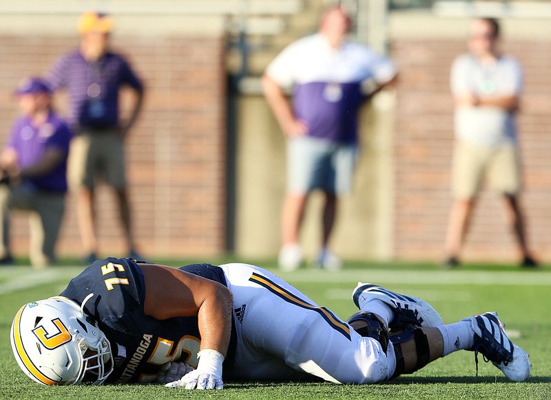 Staff photo / UTC offensive lineman Harrison Moon goes down with an injury during a home game against James Madison University on Aug. 21, 2019. The Mocs are set to play football both this spring and this fall due to the COVID-19 pandemic leading the Southern Conference to postpone league play last year.