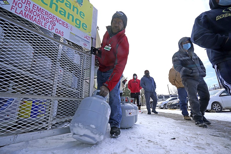 Photo by LM Oteroof The Associated Press / In this Feb. 16, 2021, file photo, Robert Webster pulls a full canister of propane for sale as customers line up to enter a grocery store in Dallas. As temperatures plunged and snow and ice whipped the state, much of Texas' power grid collapsed, followed by its water systems.