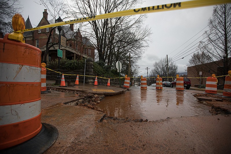 Staff photo by Troy Stolt / Water flows out of a giant hole in the ground on the corner of Palmetto and Vine streets on Monday, Feb. 22, 2021, in Chattanooga, Tenn.