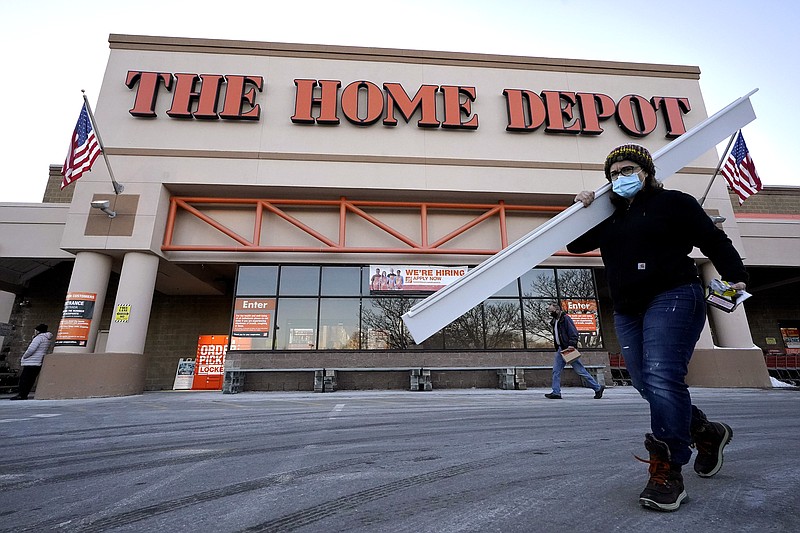 Passers-by walk near an entrance to a Home Depot home improvement store Sunday, Feb. 21, 2021, in Boston. The Home Depot's fiscal fourth-quarter sales surged 25% as the home improvement chain continues to meet the demands of consumers stuck at home and a resilient housing market. (AP Photo/Steven Senne)