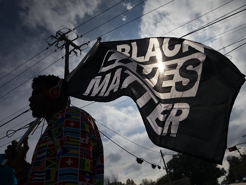 FILE - In this Dec. 12, 2020, file photo, MD Crawford carries a Black Lives Matter flag before a march in La Marque, Texas to protest the shooting of Joshua Feast, 22, by a La Marque police officer. A financial snapshot shared exclusively with The Associated Press shows the Black Lives Matter Global Network Foundation raked in just over $90 million last year. (Stuart Villanueva /The Galveston County Daily News via AP, File)