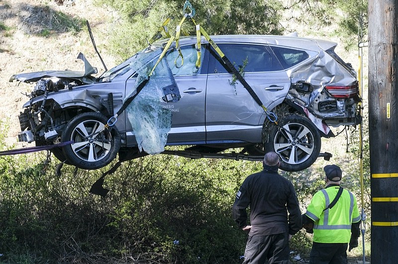 AP photo by Ringo H.W. Chiu / A crane lifts a vehicle after a rollover crash involving PGA Tour star Tiger Woods on Tuesday in Rancho Palos Verdes, a suburb of Los Angeles. Woods sustained leg injuries in the one-car wreck and was undergoing surgery, authorities and his manager said.