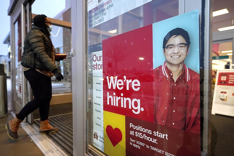 FILE - In this Feb. 9, 2021 file photo, a passer-by walks past an employment hiring sign while entering a Target store location, in Westwood, Mass. The Federal Reserve says there's evidence that hiring has picked up in recent weeks, though the job market remains badly damaged by the pandemic. In its semi-annual monetary policy report released Friday, Feb. 19, the Fed says job data compiled by payroll processor ADP indicate that employment improved modestly through early February. (AP Photo/Steven Senne, File)