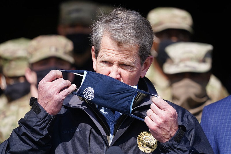 Georgia Gov. Brian Kemp removals end his face covering as he prepares to speak to reporters after touring a mass vaccination site at the Macon State Farmers Market on Friday, Feb. 19, 2021, in Atlanta. Kemp says starting Monday they plan to vaccinate 1,100 a day at the site. (AP Photo/John Bazemore)