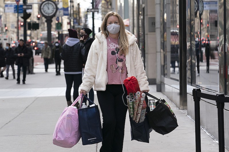 In this Dec. 10, 2020, file photo, a woman carries shopping bags in New York. Personal income was up 10% in January, leading to an increase in retail spending. (AP Photo/Mark Lennihan, File)