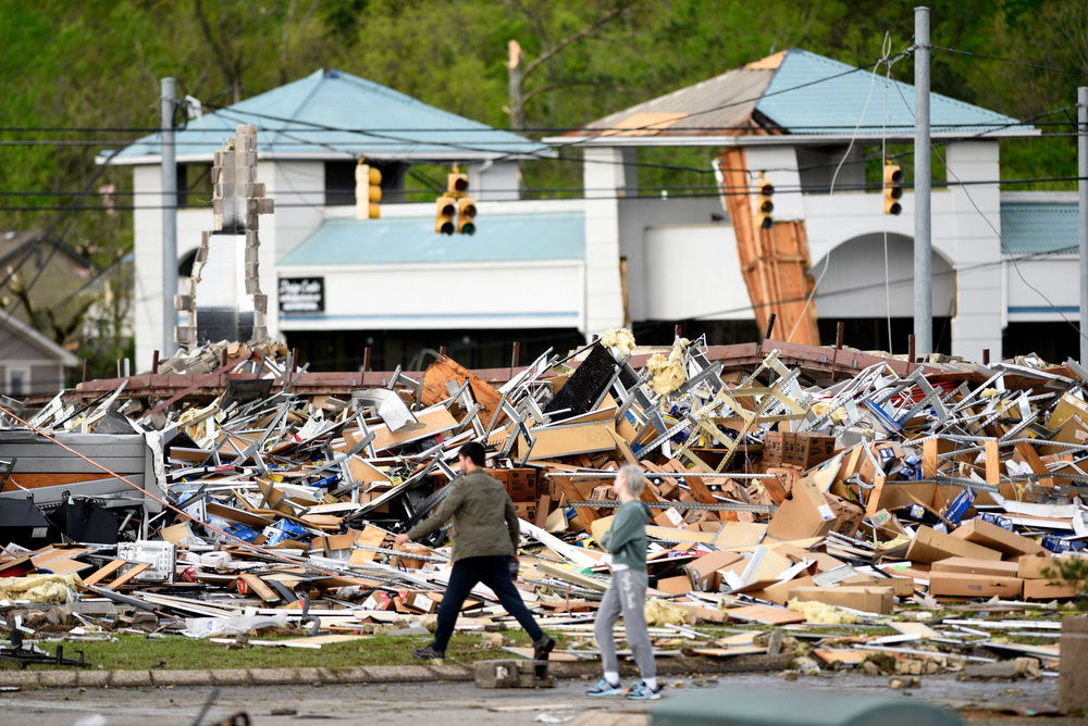 Staff Photo by Robin Rudd / People walk past the rubble of the Advanced Auto Parts Store in the 7600 block of East Brainerd Road. The Chattanooga Area was hit by severe storms on at the night of April 12, 2020.