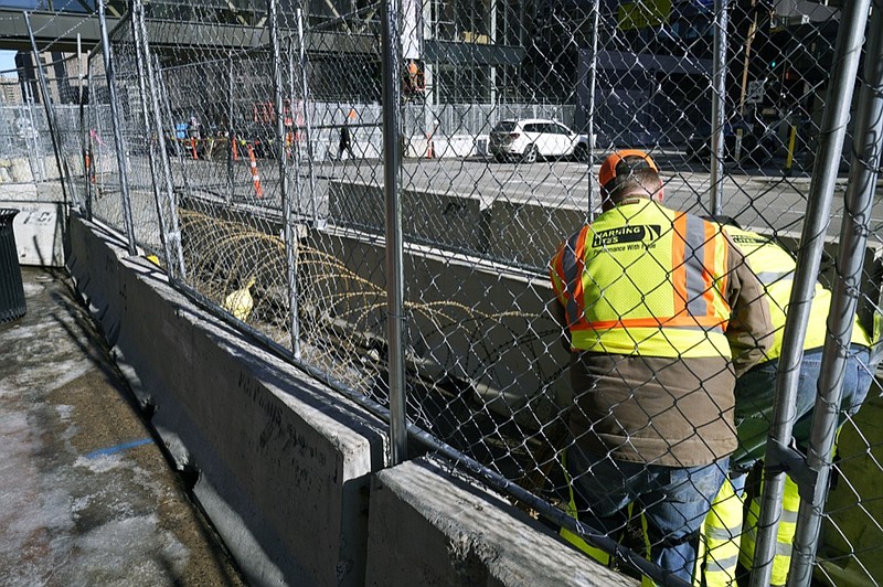 Workers install concertina wire between fenced barriers outside the Hennepin County Government Center, Wednesday, Feb. 23, 2021 in Minneapolis, as part of security in preparation for the trial of former Minneapolis police officer Derek Chauvin. (AP Photo/Jim Mone)


