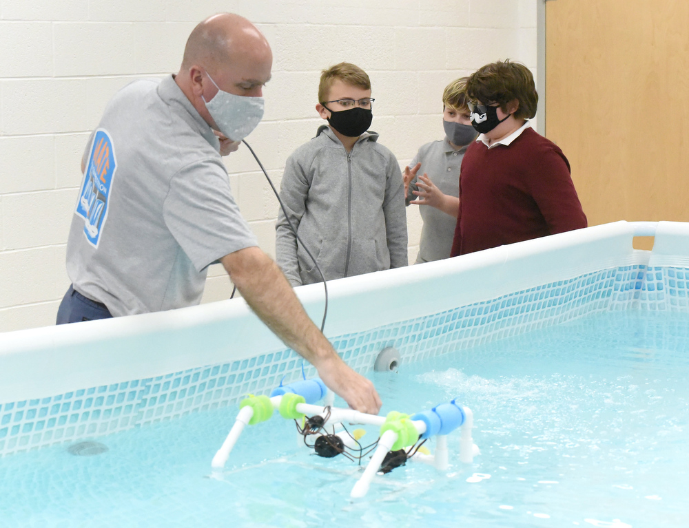Staff Photo by Matt Hamilton / Scott Rosenow works with Cash Hess, Beck Chandler and Otis Rozema, all 12, as they test a remote operated vehicle in a pool at Howard Connect Academy on Wednesday, Feb. 24, 2021.