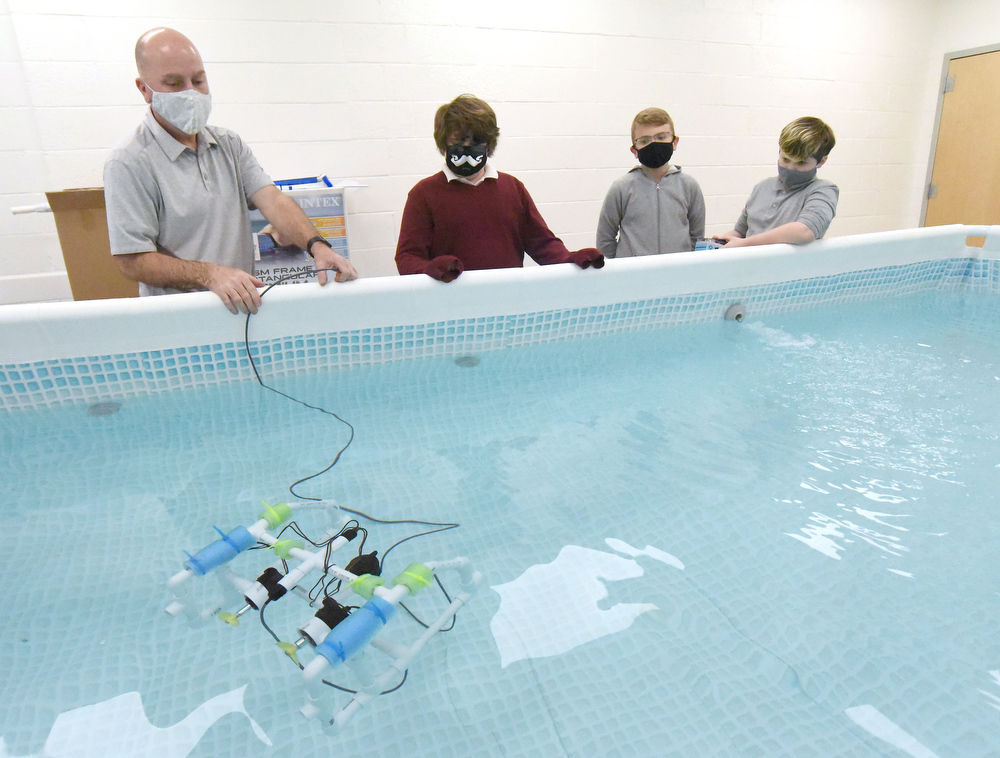 Staff Photo by Matt Hamilton / Scott Rosenow works with Otis Rozema, Cash Hess and Beck Chandler, all 12, as they test a remote operated vehicle in a pool at Howard Connect Academy on Wednesday, Feb. 24, 2021.