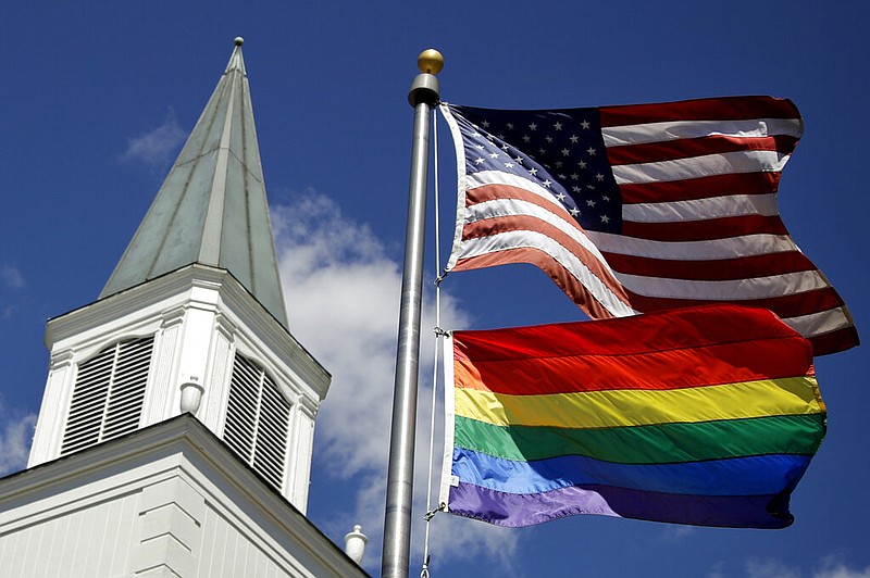 In this April 19, 2019 file photo, a gay pride rainbow flag flies along with the U.S. flag in front of the Asbury United Methodist Church in Prairie Village, Kan. Conservative leaders within the United Methodist Church unveiled plans Monday, March 1, 2021 to form a new denomination, the Global Methodist Church, with a doctrine that does not recognize same-sex marriage. The move could hasten the long-expected breakup of the UMC, America's largest mainline Protestant denomination, over differing approaches to LGBTQ inclusion. (AP Photo/Charlie Riedel, File)