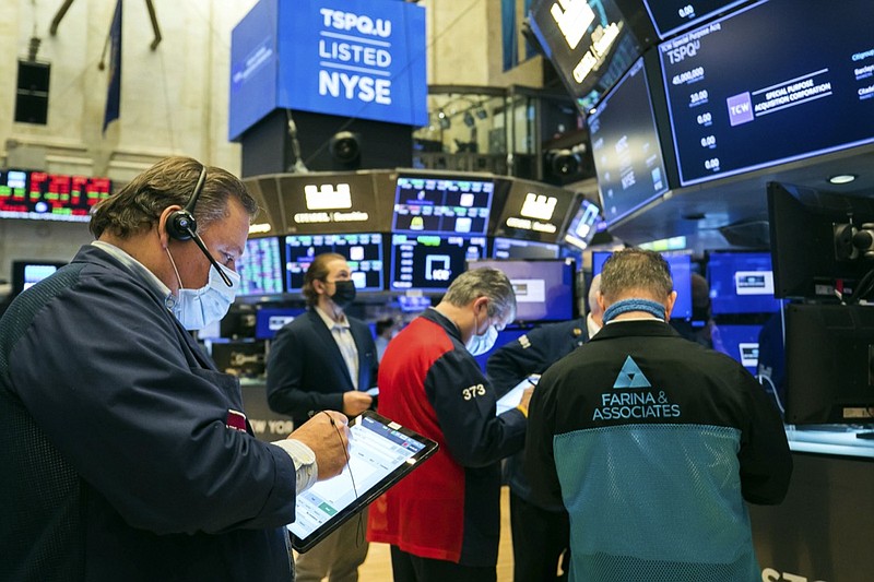 In this photo provided by the New York Stock Exchange, Tuesday, March 2, 2021, John Santiago, left, works with fellow traders on the floor. Stocks are drifting lower in morning trading on Wall Street Tuesday, giving back some of their big gains from a day earlier. (Courtney Crow/New York Stock Exchange via AP)