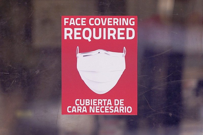 A mask required sign is displayed on the entrance to a business Tuesday, March 2, 2021, in Dallas. (AP Photo/LM Otero)