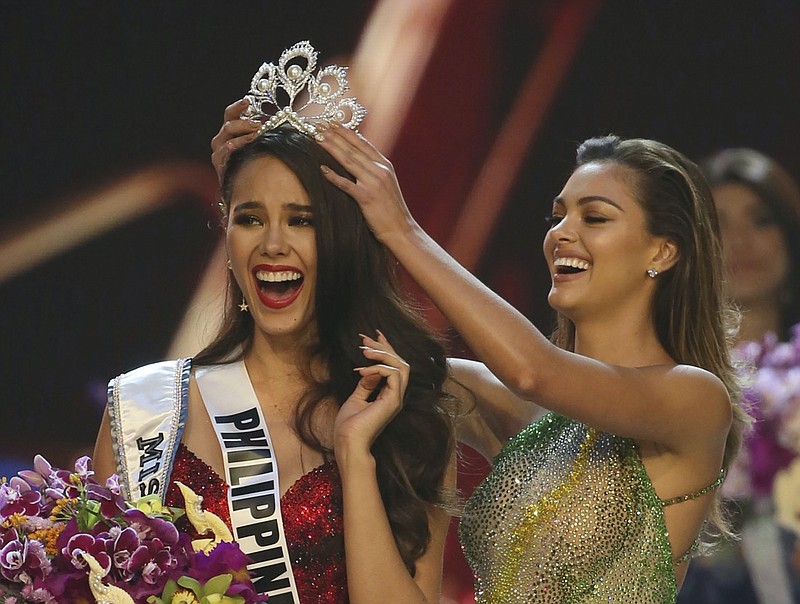 FILE - Catriona Gray of the Philippines, left, reacts as she is crowned the new Miss Universe 2018 by Miss Universe 2017 Demi-Leigh Nel-Peters during the final round of the 67th Miss Universe competition in Bangkok, Thailand, on Dec. 17, 2018. After a year and a half, the Miss Universe competition will return with a live telecast on May 16. The 69th Miss Universe will be crowned at the Seminole Hard Rock Hotel & Casino Hollywood. (AP Photo/Gemunu Amarasinghe, File)