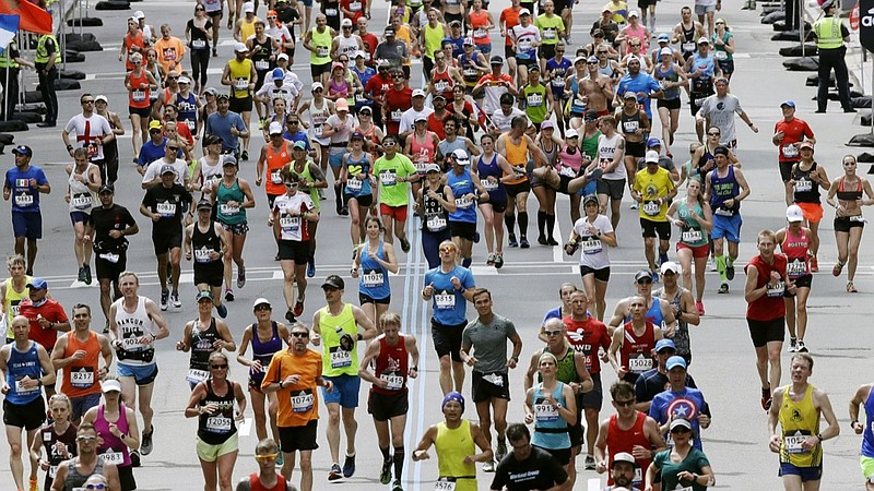 FILE - In this April 17, 2017, file photo, runners head down the stretch to the finish line in the 121st Boston Marathon in Boston. Rival camps in the running world began snapping at each other's heels in March 2021 after the Boston Athletic Association, which still hopes to hold a truncated in-person edition of the footrace in October, said it would award medals to up to 70,000 athletes if they go the distance wherever they are. (AP Photo/Charles Krupa, File)

