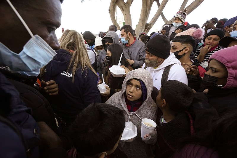 The Associated Press / Asylum seekers receive food as they wait at the border at Tijuana, Mexico, last month.