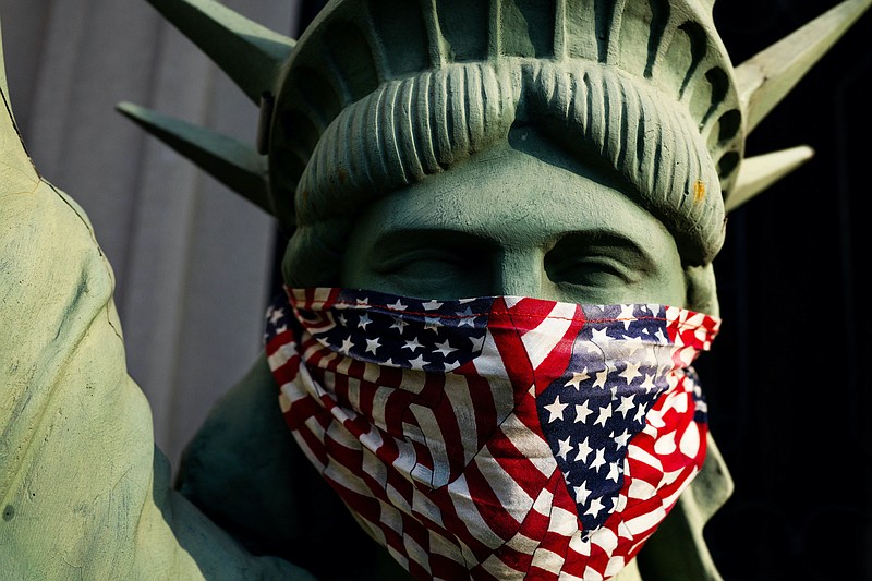 The New York Times file photo by Demetrius Freeman/A masked replica of the Statue of Liberty on the front porch of a Brooklyn home in April.