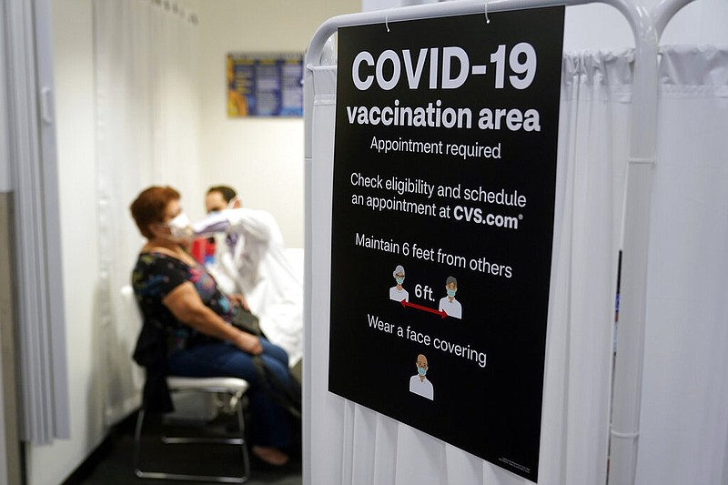 In this March 1, 2021, file photo, a patient receives a shot of the Moderna COVID-19 vaccine next to a guidelines sign at a CVS Pharmacy branch in Los Angeles. More than 27 million Americans fully vaccinated against the coronavirus will have to keep waiting for guidance from U.S. health officials for what they should and shouldn't do. The Biden administration said Friday, March 5, it's focused on getting the guidance right and accommodating emerging science. (AP Photo/Marcio Jose Sanchez, File)