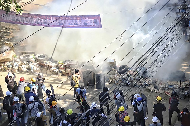 Anti-coup protesters maintain their position behind a barricade despite smoke from tear gas in San Chaung township in Yangon, Myanmar Friday, Mar. 5, 2021. Demonstrators defy growing violence by security forces and stage more anti-coup protests ahead of a special U.N. Security Council meeting on the country's political crisis. (AP Photo)