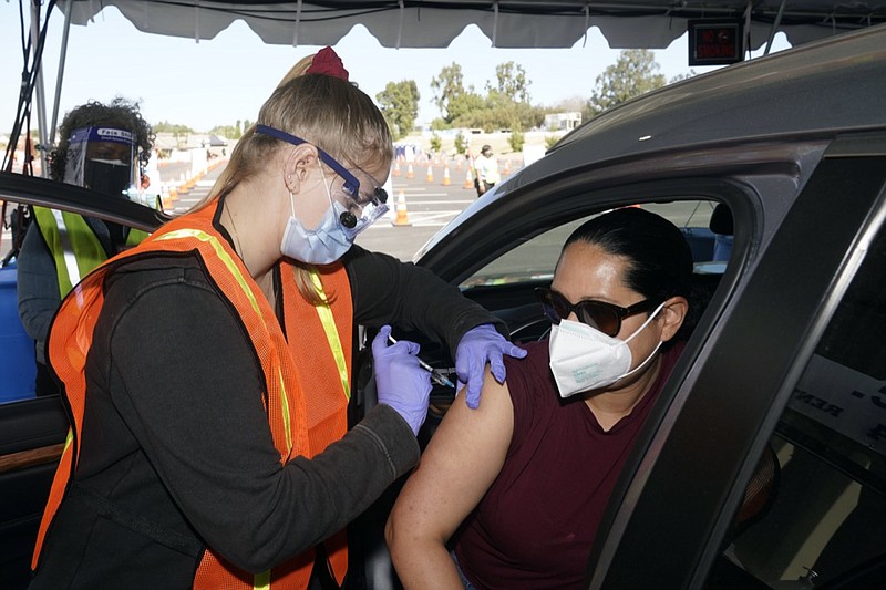 FILE - In this March 2, 2021, file photo, Vanessa Guerra, at right, a special education teacher at Grant Elementary School in Hollywood, receives a shot of the Moderna COVID-19 vaccine from nurse Kelly Mendoza at a site for employees of the Los Angeles school district in the parking lot of SOFI Stadium in Inglewood, Calif. Cities and states are rapidly expanding access to vaccines as the nation races to head off a resurgence in coronavirus infections and reopen schools and businesses battered by the pandemic. (AP Photo/Marcio Jose Sanchez, File)