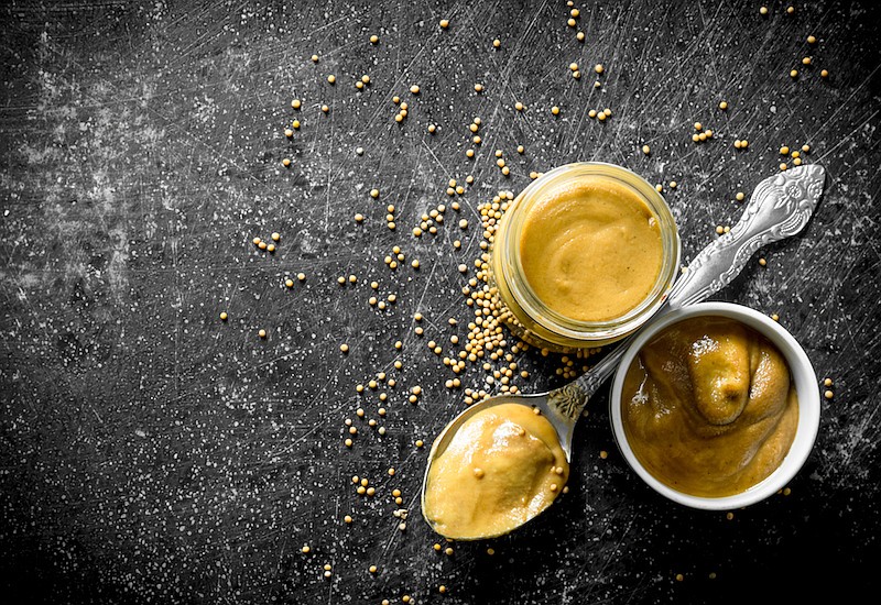 Mustard in a glass jar, spoon and bowl. / Photo credit: Getty Images/iStock/Olesia Shadrina