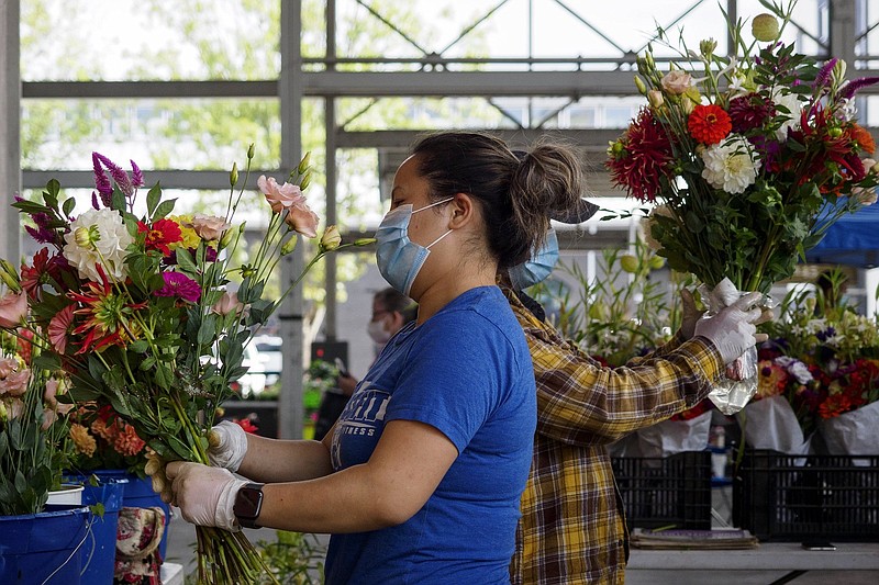 Staff photo by C.B. Schmelter / Davoua Vang, left, and Paul Herr put together bouquets at the Herr Flowers booth at the Chattanooga Market at the First Horizon Pavilion in September 202o. The couple have decided to close their flower business after nearly a decade of operating at the Chattanooga Market.