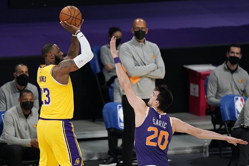 Los Angeles Lakers forward LeBron James, left, shoots as Phoenix Suns forward Dario Saric defends during the first half of an NBA basketball game Tuesday, March 2, 2021, in Los Angeles. (AP Photo/Mark J. Terrill)

