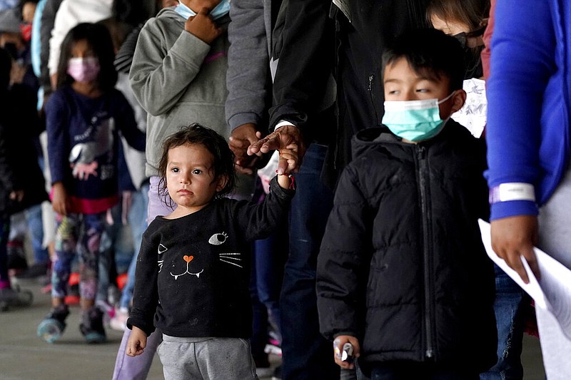 Migrant children are seen with adults as they wait in line to get a COVID-19 test before given travel instructions at a bus station, Wednesday, March 17, 2021, in Brownsville, Texas. A surge of migrants on the Southwest border has the Biden administration on the defensive. The head of Homeland Security acknowledged the severity of the problem Tuesday but insisted it's under control and said he won't revive a Trump-era practice of immediately expelling teens and children. An official says U.S. authorities encountered nearly double the number children traveling alone across the Mexican border in one day this week than on an average day last month. (AP Photo/Julio Cortez)