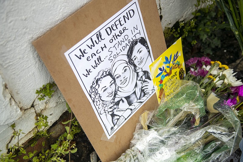 In this March 17, 2021, file photo, flowers, candles and signs are displayed at a makeshift memorial outside of the Gold Spa following a shooting in Atlanta. While the U.S. has seen mass killings in recent years where police said gunmen had racist or misogynist motivations, advocates and scholars say the shootings this week at three Atlanta-area massage parlors targeted a group of people marginalized in more ways than one, in a crime that stitches together stigmas about race, gender, migrant work and sex work. (Alyssa Pointer/Atlanta Journal-Constitution via AP, File)