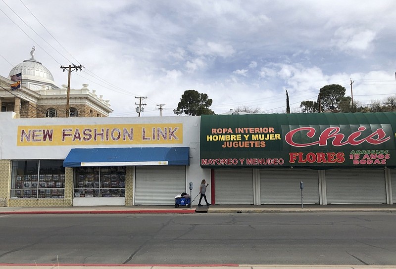 A woman walks past two out-of-business clothing stores located steps away from the U.S.-Mexico border on March 15, 2021 in Nogales, Ariz. (AP Photo/Suman Naishadham)


