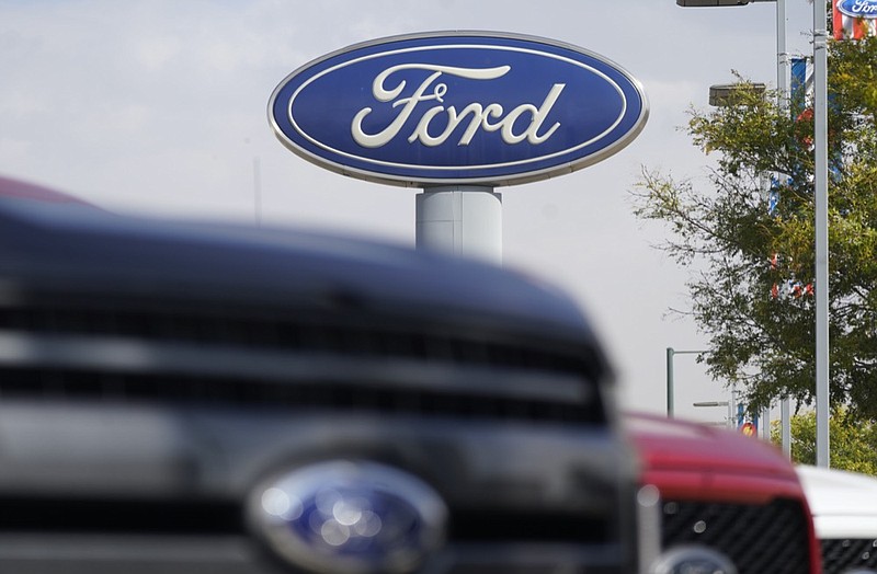 FILE - In this Sunday, Oct. 11, 2020, file photo, the company logo hangs over a row of 2020 F-150 pickup trucks at a Ford dealership, in Denver. (AP Photo/David Zalubowski, File)


