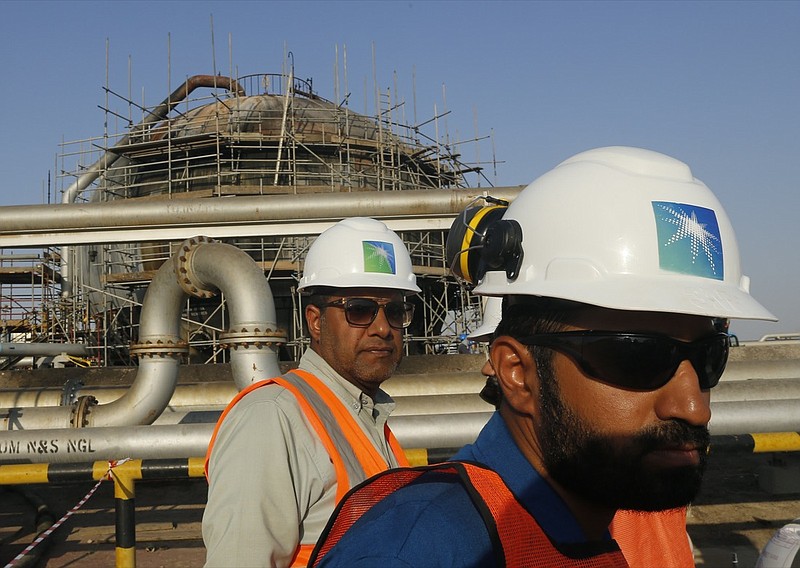 In this Sept. 20, 2019, file photo, engineers walk in front of an oil separator at a Saudi Aramco processing facility in Abqaiq, Saudi Arabia. Saudi Arabia's state-backed oil giant Aramco announced Sunday, March 21, 2021, that its 2020 profits fell sharply in 2020 to $49 billion, a big drop that came as the coronavirus pandemic roiled global energy markets. (AP Photo/Amr Nabil, File)