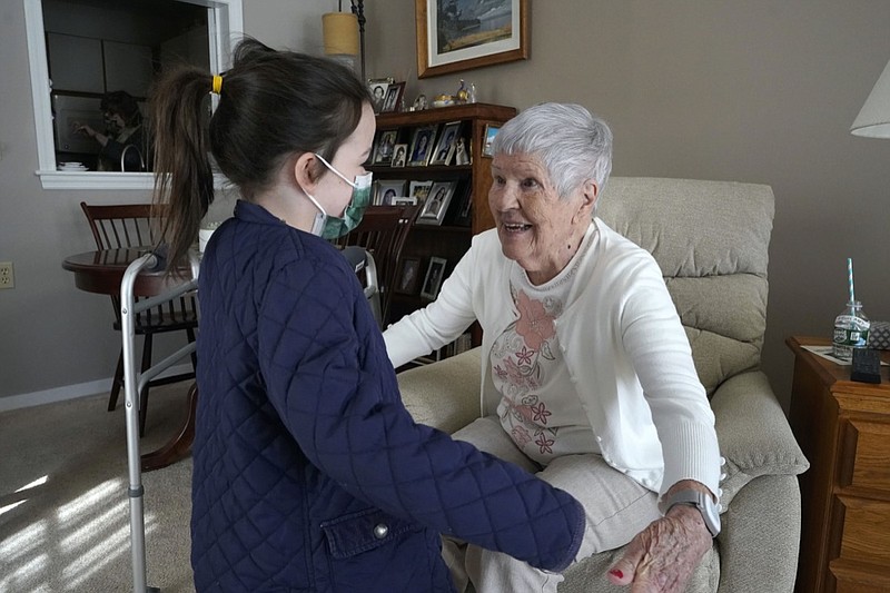 Eileen Quinn, 98, right, a resident at New Pond Village retirement community, in Walpole, Mass., greets her great-granddaughter Maeve Whitcomb, 6, of Norwood, Mass., left, Sunday, March 21, 2021, at the retirement community, in Walpole. Quinn said it was the first time she had been able to visit with her great-grandchildren in her apartment since the coronavirus pandemic began. (AP Photo/Steven Senne)

