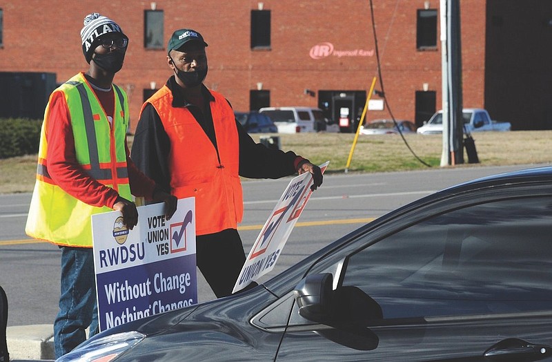 Tray Ragland, left, and Kim Hickerson of the Retail, Wholesale and Department Store Union hold signs outside an Amazon facility where labor is trying to organize workers on Tuesday, Feb. 9, 2021. For Amazon, a successful effort could motivate other workers to organize. But a contract could take years, and Amazon has a history of crushing labor organizing. (AP Photo/Jay Reeves)