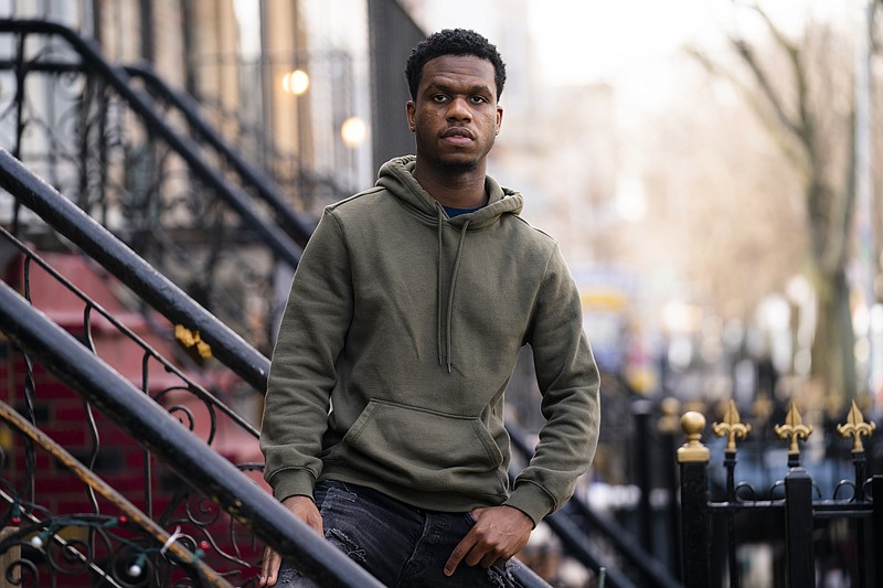 Mikel Haye poses for a portrait on his stoop, Friday, March 12, 2021, in the Brooklyn borough of New York. Haye, who was forced into performing a financial triage after he lost all three of his part-time jobs shortly after the pandemic struck. He was scrambling to pay the bills on a Brooklyn apartment he shares with his unemployed mother and two brothers while deciding how to spend whatever money was left: On food? The car insurance? His phone bill? (AP Photo/John Minchillo)