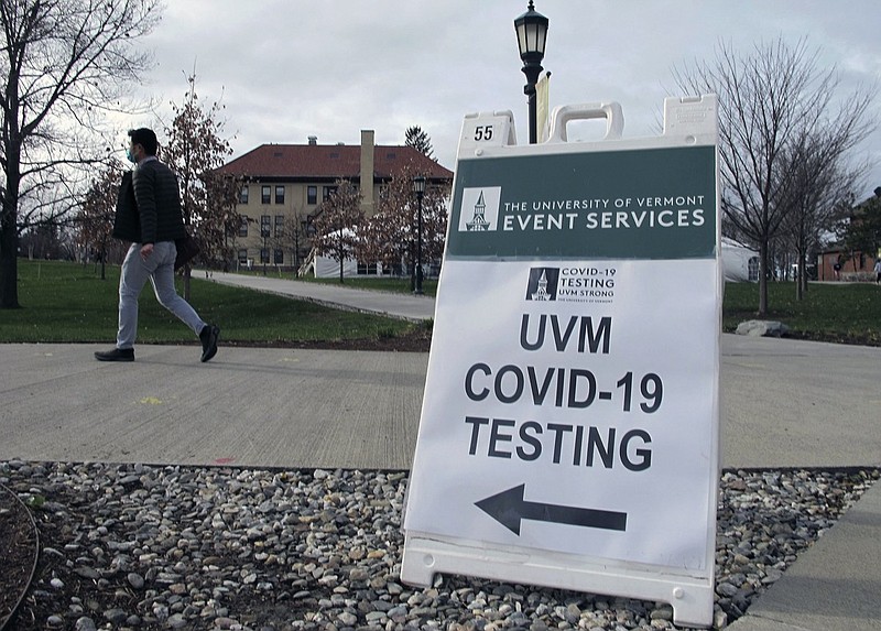 FILE - In this Nov. 12, 2020, file photo, a University of Vermont student walks toward a tent leading to a COVID-testing site on campus in Burlington, Vt. Colleges throughout the U.S. are assuring students that this coming fall will bring a return to in-person classes, intramural sports and mostly full dormitories. But those promises come with asterisks. (AP Photo/Lisa Rathke, File)