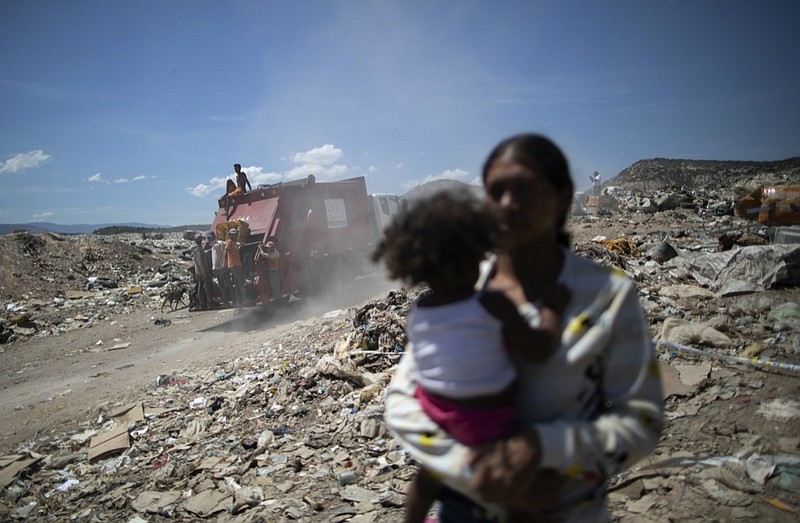 FILE - In this March 3, 2021 file photo, youths who cull through trash for items to resell ride on the back of a garbage truck entering the Pavia landfill on the outskirts of Barquisimeto, Venezuela. A U.S. senator urged the Biden administration Tuesday, March 23, 2021, to lift a ban on diesel fuel swaps with Venezuela, adding to pressure from some Democrats and aid workers who argue sanctions are worsening the South American country's dire humanitarian crisis. (AP Photo/Ariana Cubillos, File)