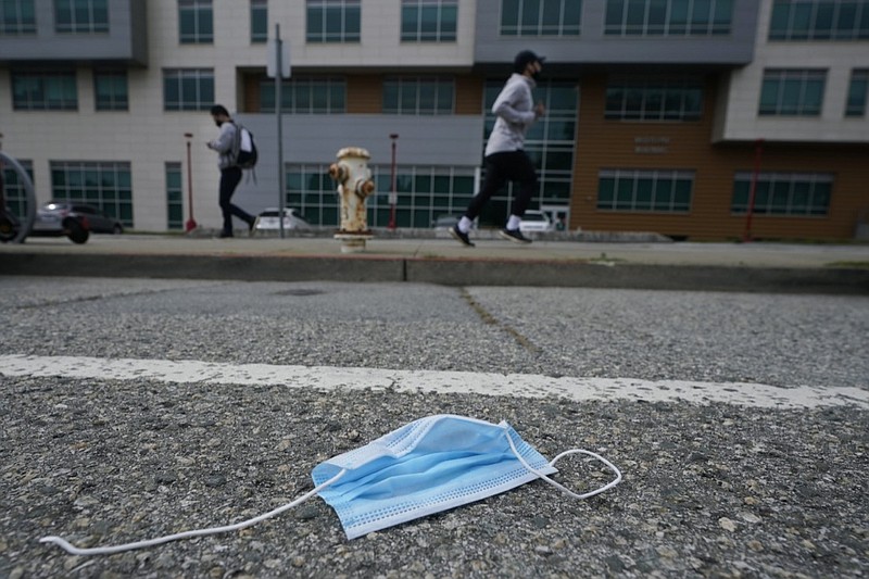 A discarded face mask lies in the street in San Francisco, Wednesday, March 17, 2021. Disposable masks, gloves and other personal protective equipment have safeguarded untold lives during the pandemic. They're also creating a worldwide environmental problem, littering streets and sending an influx of harmful plastic into landfills and oceans. (AP Photo/Jeff Chiu)