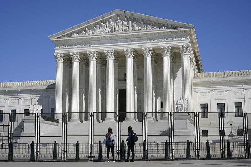 People view the Supreme Court building from behind security fencing on Capitol Hill in Washington, Sunday, March 21, 2021, after portions of an outer perimeter of fencing were removed overnight to allow public access. (AP Photo/Patrick Semansky)


