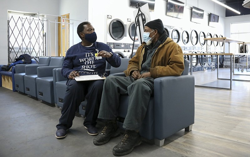Herman Simmons, left, makes a vaccination appointment for Theopulis Polk, right, at a Chicago laundromat on Saturday, March 6, 2021. Simmons is a community outreach worker enlisted by Saint Anthony Hospital. ''I see myself as my brother's keeper. I don't try to force them. I'm persistent,'' he said. (AP Photo/Teresa Crawford)


