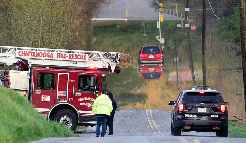 Staff Photo by Robin Rudd /  Chattanooga Fire, Police and Public Works Department personal investigate a stranded vehicle in the floodwaters of Mackey Branch on Davidson Road in East Brainerd Friday.  The road is protected by recently installed warning gates and flashers that are activated during times of high waters.  