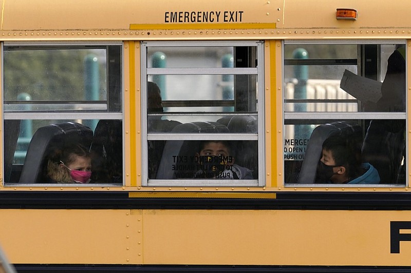 FILE - In this Thursday, Nov. 19, 2020, file photo, elementary school students sit on board a school bus after attending in-person classes at school in Wheeling, Ill. (AP Photo/Nam Y. Huh, File)


