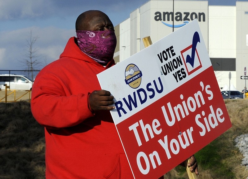 FILE - In this Tuesday, Feb. 9, 2021, file photo, Michael Foster of the Retail, Wholesale and Department Store Union holds a sign outside an Amazon facility where labor is trying to organize workers in Bessemer, Ala. Nearly 6,000 Amazon warehouse workers in Bessemer are deciding whether they want to form a union, the biggest labor push in the online shopping giant's history. Mail-in voting started in early February. Ballots must be received by the end of Monday March 29, 2021. The National Labor Relations Board starts counting votes the next day. (AP Photo/Jay Reeves, File)