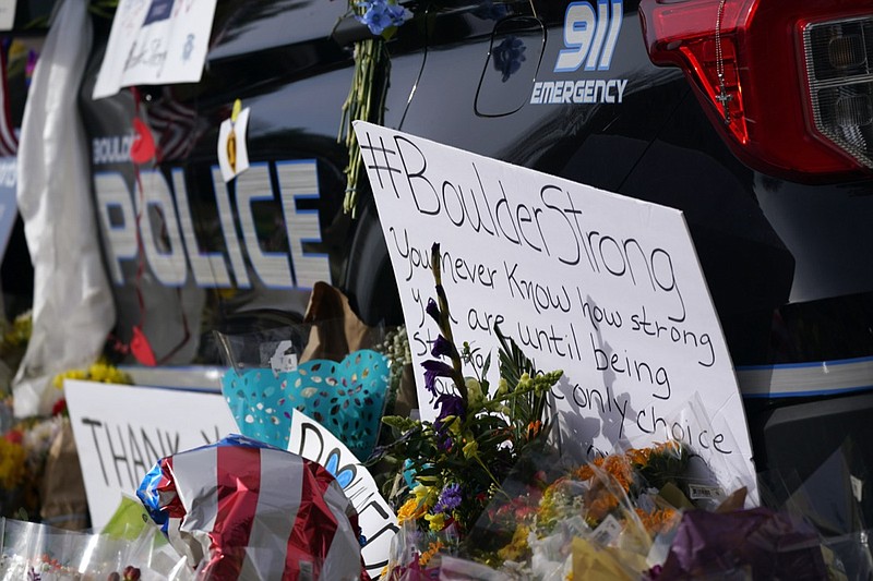 Signs, floral bouquets and tributes stand along side a police cruiser parked in front of the Boulder, Colo., Police Department in honor of fallen officer Eric Talley, who was one of 10 victims in a mass shooting at a King Soopers grocery store, before a news conference about the ongoing investigation outside police headquarters Friday, March 26, 2021, in Boulder, Colo. (AP Photo/David Zalubowski)