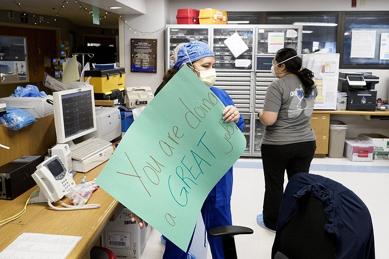 Staff photo by C.B. Schmelter / Clinical staff leader nurse Heather Atkinson carries an encouraging sign over to a patient's room inside the COVID intensive care unit at Erlanger on Monday, Feb. 22, 2021 in Chattanooga, Tenn.