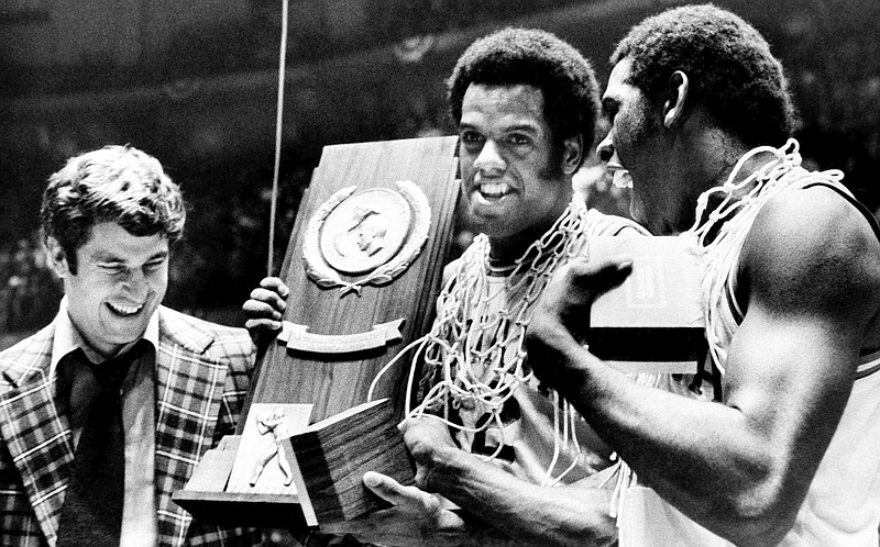 Indiana coach Bobby Knight, left, and team members Scott May, center, and Quinn Buckner, right, celebrate with the trophy after winning the 1976 NCAA Basketball Championship by beating Michigan 86-68.