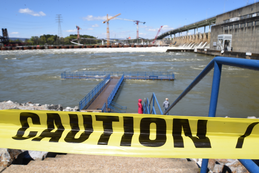Staff Photo by Matt Hamilton / Caution tape warns of the high water partially covering the fishing pier at the Chickamauga Dam on Thursday, April 1, 2021.